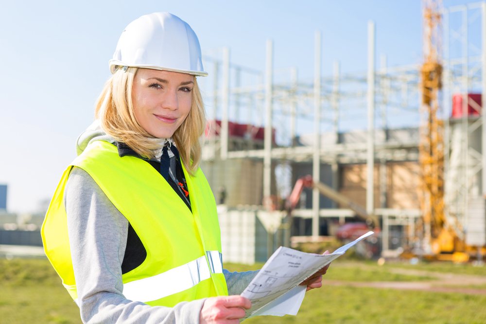 A Bayside team member in a hard hat and high-visibility vest reviewing project plans on a job site